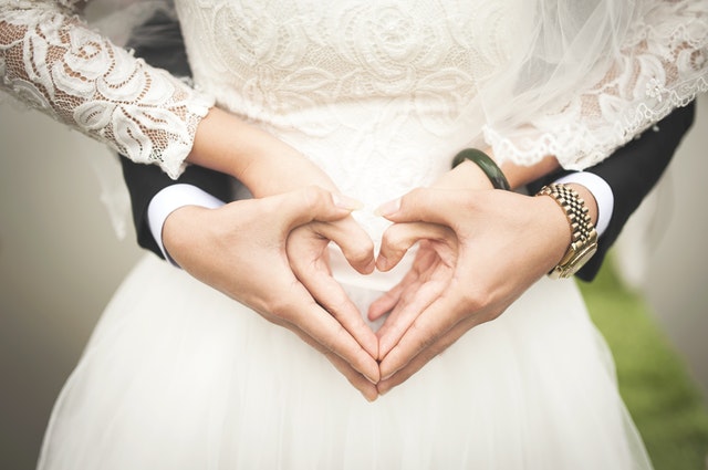 Bride and groom forming heart shape with hands