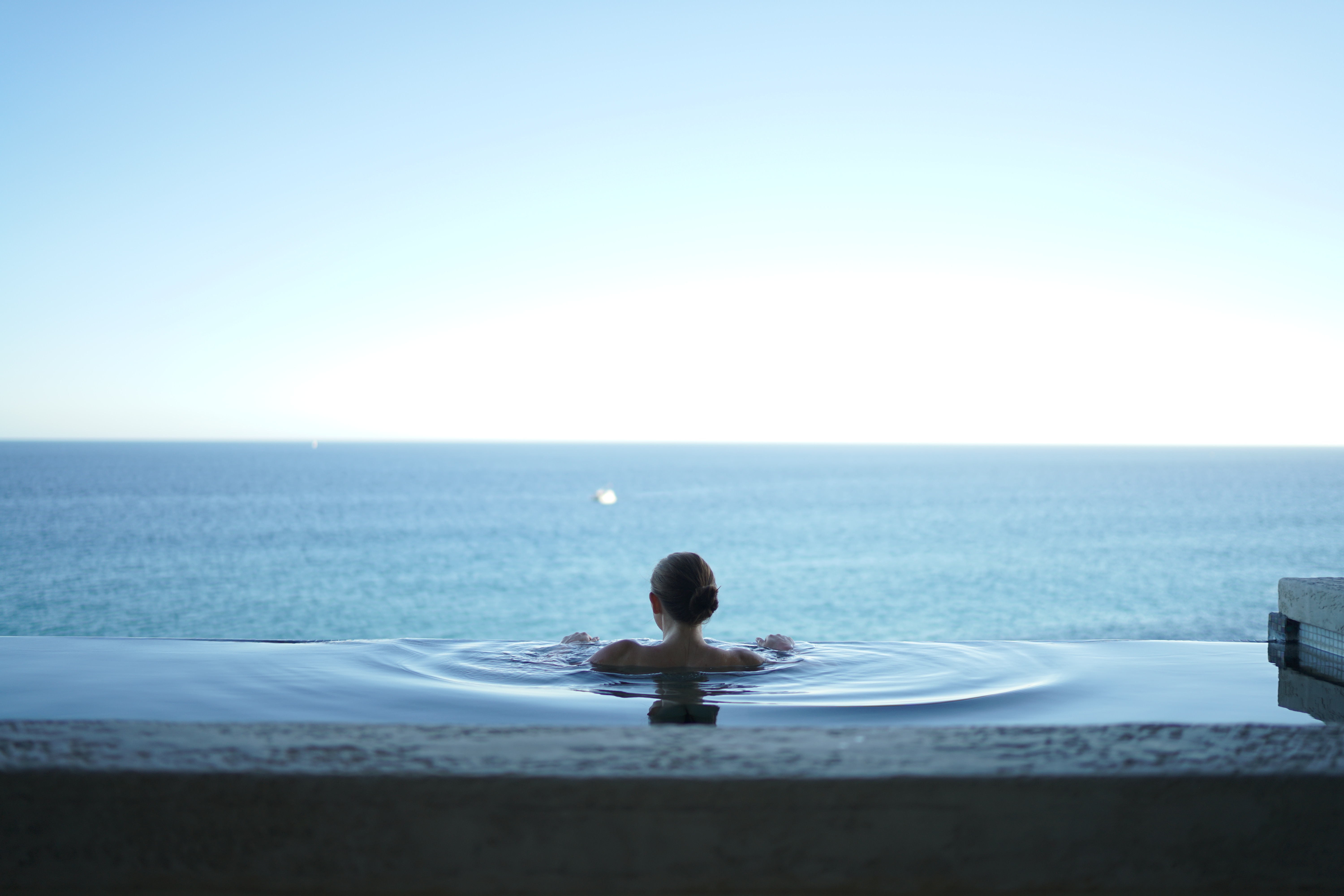 Woman-in-infinity-pool-looking-out-at-horizon-in-ocean